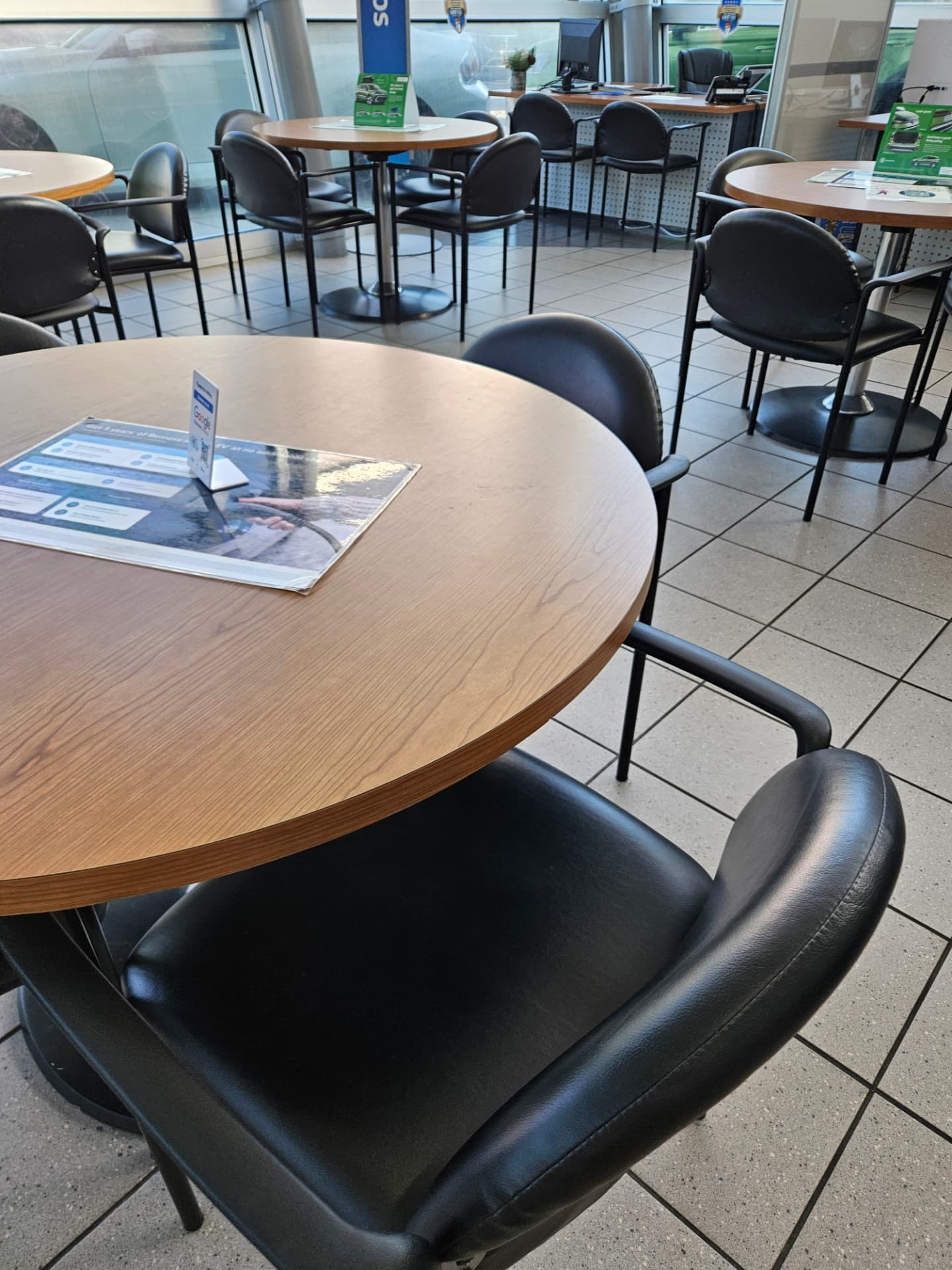Spotless car dealership customer lounge with polished tile floor, clean tables and seating