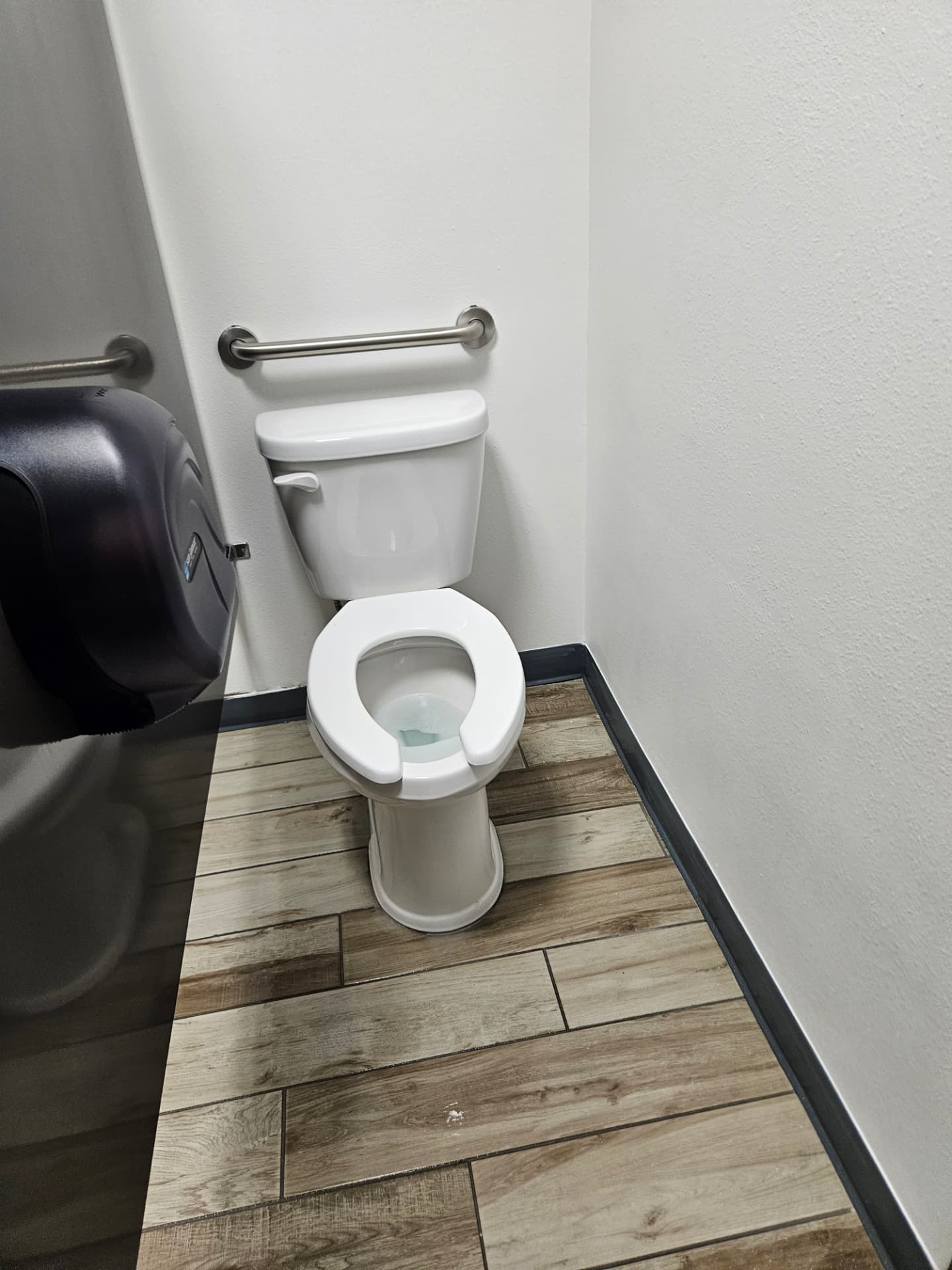 Sanitized commercial restroom stall with spotless floor tile and fixtures
